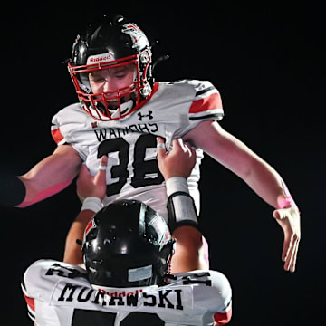 Muskego offensive lineman Parker Murawski (72) hoists fullback Bryson Hoeffler (38) after his touchdown run against Mukwonago in Classic 8 Conference game on Friday, October 17, 2025.