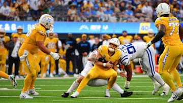 Oct 19, 2025; Inglewood, California, USA; Los Angeles Chargers quarterback Justin Herbert (10) is brought down by Indianapolis Colts defensive tackle Grover Stewart (90) in the second half at SoFi Stadium. Mandatory Credit: Gary A. Vasquez-Imagn Images