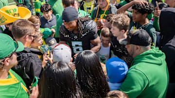 Combat Ducks running back Noah Whittington signs autographs amid a mob of fans as the Fighting Ducks face off against Mighty Oregon in the Oregon Ducks spring game on April 26, 2025, at Autzen Stadium in Eugene.