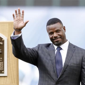 Seattle Mariners former player Ken Griffey Jr. smiles next to his Hall of Fame plaques during his number retirement ceremony before the start of a game against the Los Angeles Angels at Safeco Field in 2016.