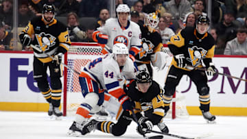 Dec 29, 2024; Pittsburgh, Pennsylvania, USA;  Pittsburgh Penguins center Cody Glass (19) clears the puck away from New York Islanders center Jean-Gabriel Pageau (44) during the third period at PPG Paints Arena. Mandatory Credit: Charles LeClaire-Imagn Images