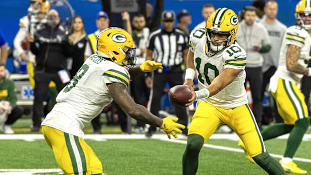 Green Bay Packers quarterback Jordan Love (10) hands the ball off to running back Josh Jacobs (8).