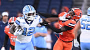 Oct 31, 2025; Syracuse, New York, USA; North Carolina Tar Heels running back Demon June (12) gives a stiff arm to Syracuse Orange defensive back Braheem Long Jr. (0) while scoring a touchdown in the third quarter at the JMA Wireless Dome. Mandatory Credit: Mark Konezny-Imagn Images