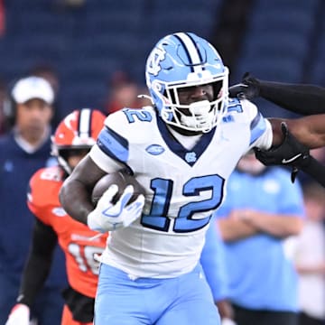 Oct 31, 2025; Syracuse, New York, USA; North Carolina Tar Heels running back Demon June (12) gives a stiff arm to Syracuse Orange defensive back Braheem Long Jr. (0) while scoring a touchdown in the third quarter at the JMA Wireless Dome. Mandatory Credit: Mark Konezny-Imagn Images