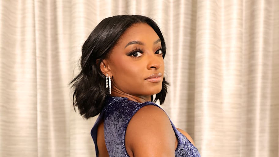Simone Biles turns toward the camera while posing for a photo.