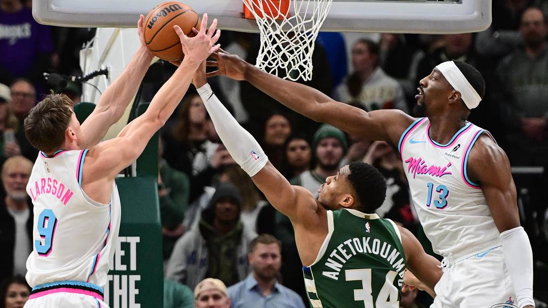 Jan 23, 2025; Milwaukee, Wisconsin, USA;  Miami Heat guard Pelle Larsson (9) and center Bam Adebayo (13) reach for a rebound against Milwaukee Bucks forward Giannis Antetokounmpo (34) in the first quarter at Fiserv Forum. Mandatory Credit: Benny Sieu-Imagn Images
