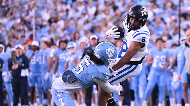 Nov 22, 2025; Chapel Hill, North Carolina, USA; Duke Blue Devils wide receiver Jayden Moore (8) twists from a tackle by North Carolina Tar Heels defensive back Gavin Gibson (5) during the first half at Kenan Stadium. Mandatory Credit: William Howard-Imagn Images