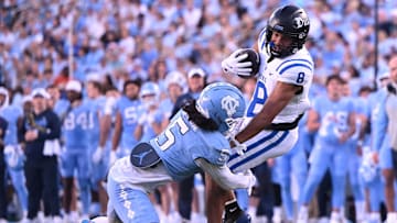 Nov 22, 2025; Chapel Hill, North Carolina, USA; Duke Blue Devils wide receiver Jayden Moore (8) twists from a tackle by North Carolina Tar Heels defensive back Gavin Gibson (5) during the first half at Kenan Stadium. Mandatory Credit: William Howard-Imagn Images