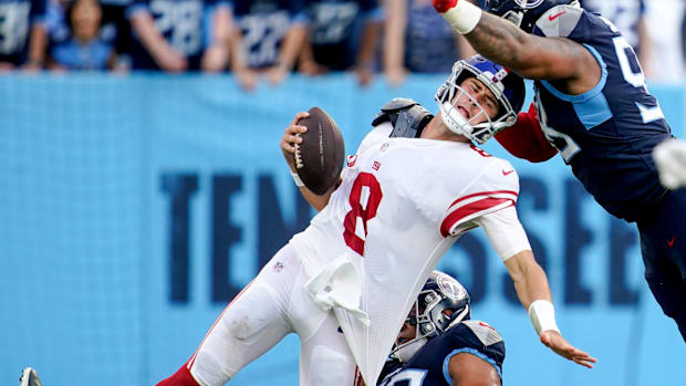 Colts QB Daniel Jones (white and red jersey) gets sacked behind the line of scrimmage by multiple defenders.