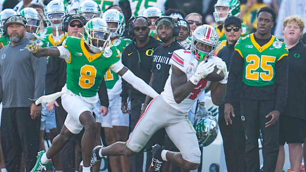 Ohio State Buckeyes wide receiver Jeremiah Smith (4) catches a pass in front of Oregon Ducks quarterback Dillon Gabriel (8) d