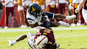 West Virginia Mountaineers Fred Perry (5) jumps over Arizona State Sun Devils Jeff Sims (2) and West Virginia Mountaineers Jordan Walker (4) during a game at Mountain America Stadium in Tempe on Nov. 15, 2025.