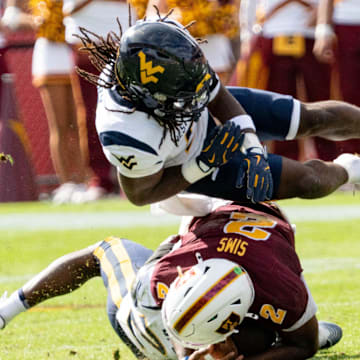 West Virginia Mountaineers Fred Perry (5) jumps over Arizona State Sun Devils Jeff Sims (2) and West Virginia Mountaineers Jordan Walker (4) during a game at Mountain America Stadium in Tempe on Nov. 15, 2025.