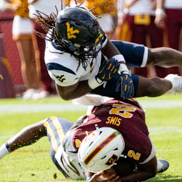 West Virginia Mountaineers Fred Perry (5) jumps over Arizona State Sun Devils Jeff Sims (2) and West Virginia Mountaineers Jordan Walker (4) during a game at Mountain America Stadium in Tempe on Nov. 15, 2025.