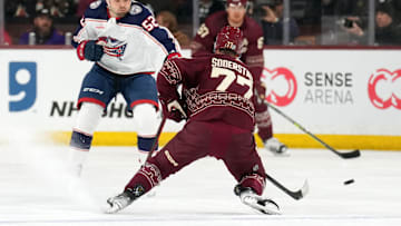 Feb 19, 2023; Tempe, Arizona, USA; Arizona Coyotes defenseman Victor Soderstrom (77) moves the puck by Columbus Blue Jackets right wing Emil Bemstrom (52) during the first period at Mullett Arena. Mandatory Credit: Joe Camporeale-Imagn Images