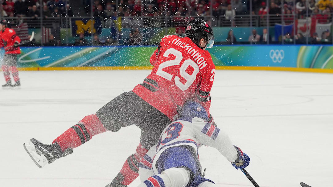 Feb 22, 2026; Milan, Italy; Nathan MacKinnon (29) of Canada and Quinn Hughes (43) of the United States in action in the men's ice hockey gold medal game during the Milano Cortina 2026 Olympic Winter Games at Milano Santagiulia Ice Hockey Arena. Mandatory Credit: Amber Searls-Imagn Images