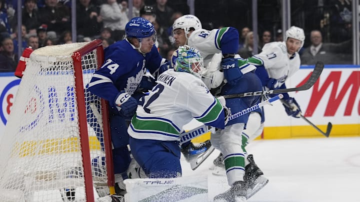 Jan 11, 2025; Toronto, Ontario, CAN; Toronto Maple Leafs forward Bobby McMann (74) gets knocked into the net by Vancouver Canucks defenseman Noah Juulsen (47) as  goaltender Kevin Lankinen (32) tries to get out of the way during the third period at Scotiabank Arena. Mandatory Credit: John E. Sokolowski-Imagn Images