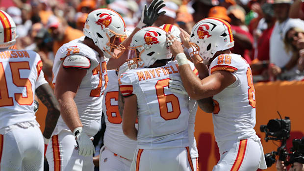 Bucs teammates celebrate in a group wearing throwback uniforms