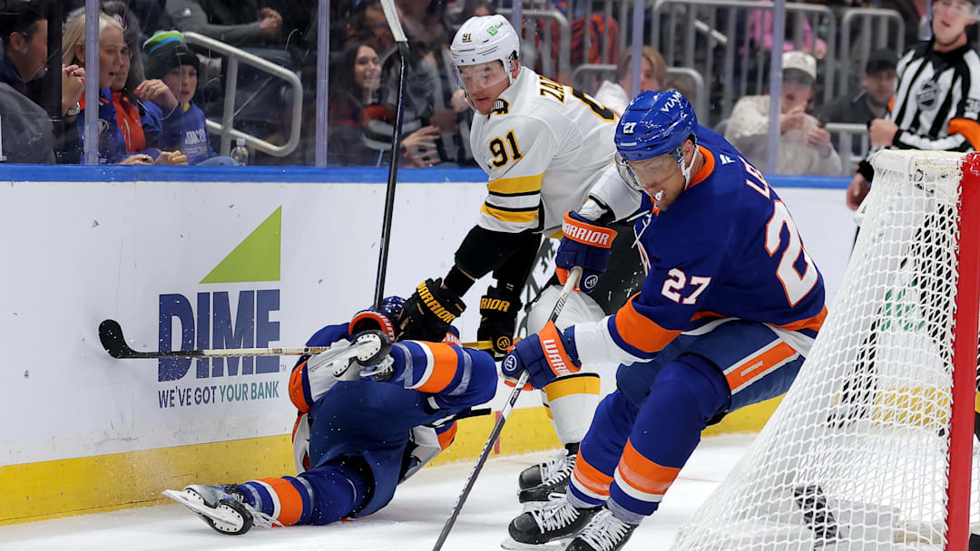Nov 4, 2025; Elmont, New York, USA; New York Islanders left wing Anders Lee (27) controls the puck against the Boston Bruins as Bruins defenseman Nikita Zadorov (91) hits Islanders defenseman Matthew Schaefer (48) during the second period at UBS Arena. Mandatory Credit: Brad Penner-Imagn Images