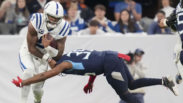 Colts quarterback Anthony Richardson (white jersey with blue trim) tries to avoid a defender going for a tackle.
