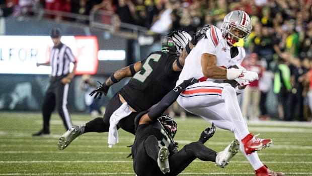 Oregon defensive backs Kobe Savage (5) and Brandon Johnson trip up Ohio State wide receiver Emeka Egbuka during their game at