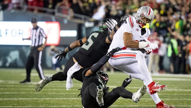 Oregon defensive backs Kobe Savage (5) and Brandon Johnson trip up Ohio State wide receiver Emeka Egbuka during their game at