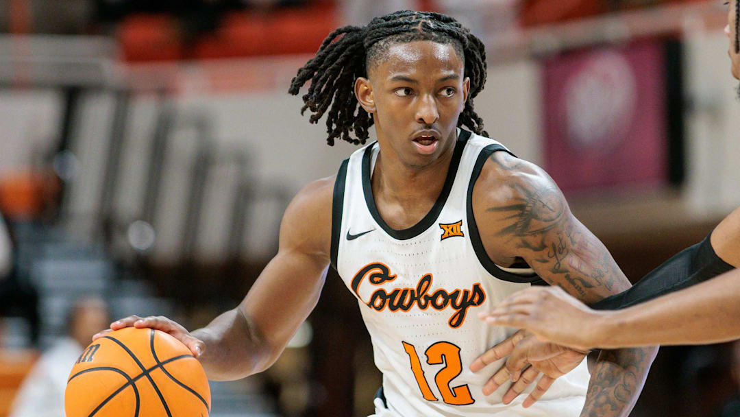 Feb 28, 2024; Stillwater, Oklahoma, USA; Oklahoma State Cowboys guard Javon Small (12) drives around UCF Knights forward Omar Payne (5) during the second half at Gallagher-Iba Arena. Mandatory Credit: William Purnell-Imagn Images