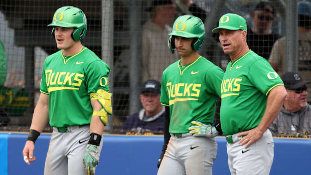 Oregon head coach Mark Wasikowski (44, R) talks to third baseman Carter Garate (3, C) and outfielder Bryce Boettcher (28, L) 