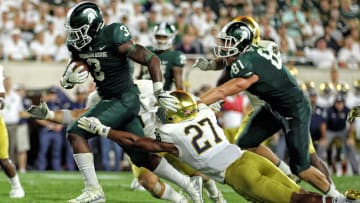 Sep 23, 2017; East Lansing, MI, USA; Michigan State Spartans running back LJ Scott (3) runs though the tackle of Notre Dame Fighting Irish cornerback Julian Love (27) during the first half a game at Spartan Stadium. Mandatory Credit: Mike Carter-USA TODAY Sports