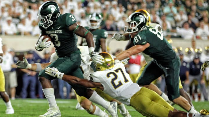 Sep 23, 2017; East Lansing, MI, USA; Michigan State Spartans running back LJ Scott (3) runs though the tackle of Notre Dame Fighting Irish cornerback Julian Love (27) during the first half a game at Spartan Stadium. Mandatory Credit: Mike Carter-USA TODAY Sports