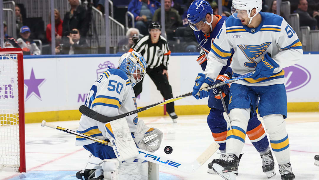 Nov 22, 2025; Elmont, New York, USA; St. Louis Blues goaltender Jordan Binnington (50) defends the net as left wing Anders Lee (27) and St. Louis Blues defenseman Matthew Kessel (51) battle for control of the puck in the second period at UBS Arena. Mandatory Credit: Wendell Cruz-Imagn Images