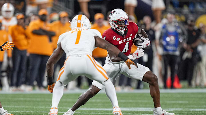 Sep 7, 2024; Charlotte, North Carolina, USA; North Carolina State Wolfpack wide receiver Dacari Collins (4) runs with the ball as Tennessee Volunteers defensive back Rickey Gibson III (1) defends during the first quarter at the Dukes Mayo Classic at Bank of America Stadium. Mandatory Credit: Jim Dedmon-Imagn Images