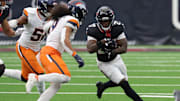 Nov 2, 2025; Houston, Texas, USA; Houston Texans running back Woody Marks (27) runs against Denver Broncos linebacker Que Robinson (51) and safety Talanoa Hufanga (9) during the second half at NRG Stadium. Mandatory Credit: Thomas Shea-Imagn Images