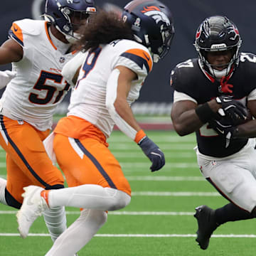 Nov 2, 2025; Houston, Texas, USA; Houston Texans running back Woody Marks (27) runs against Denver Broncos linebacker Que Robinson (51) and safety Talanoa Hufanga (9) during the second half at NRG Stadium. Mandatory Credit: Thomas Shea-Imagn Images
