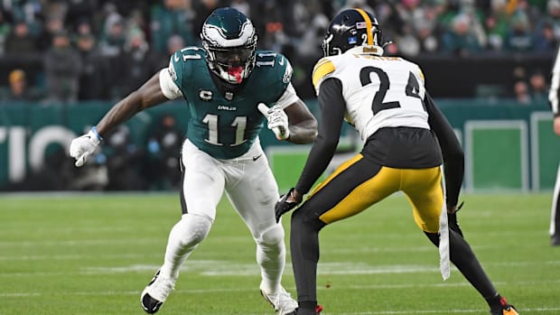 football player in white uniform matches up against receiver in green uniform