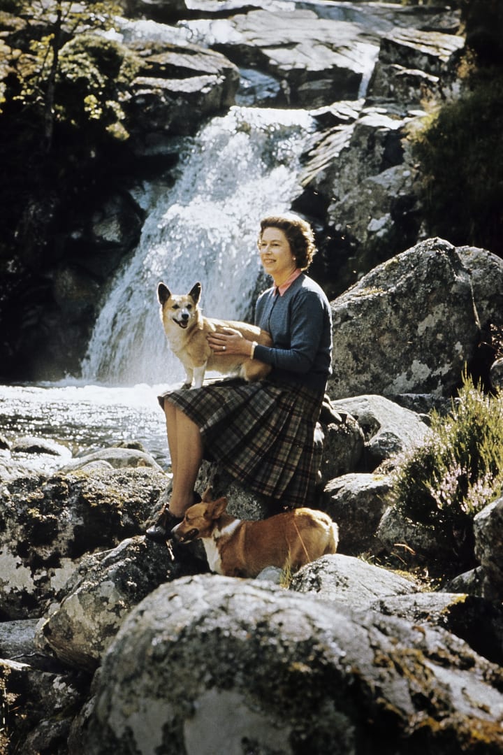 Queen Elizabeth II sits with two corgis beside a waterfall on the Garbh Allt stream at Balmoral Castle, Scotland, in 1971