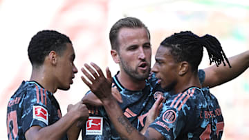 Bayern Munich forwards Jamal Musiala, Harry Kane, and Michael Olise celebrating a goal against Werder Bremen.