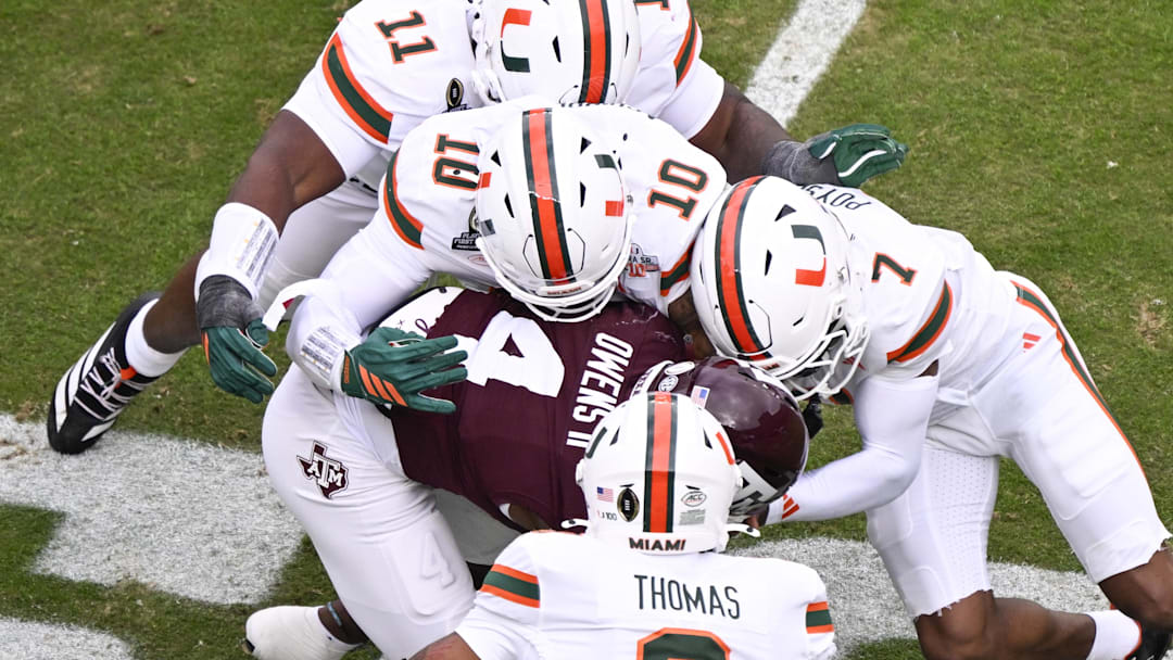 Dec 20, 2025; College Station, TX, USA; Texas A&M Aggies running back Rueben Owens II (4) is tackled by Miami Hurricanes defensive lineman David Blay (11), linebacker Jr. Raul Aguirre (10), safety Zechariah Poyser (7), and defensive back Jakobe Thomas (8) during first quarter of the first round game of the CFP National Playoff at Kyle Field. Mandatory Credit: Jerome Miron-Imagn Images