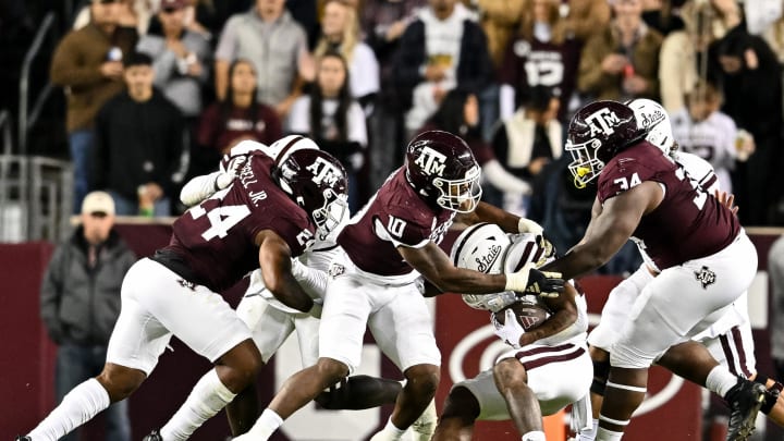 Nov 11, 2023; College Station, Texas, USA; Texas A&M Aggies defensive lineman Fadil Diggs (10) and defensive lineman Isaiah Raikes (34) tackle Mississippi State Bulldogs running back Jeffery Pittman (25) during the third quarter at Kyle Field. Mandatory Credit: Maria Lysaker-USA TODAY Sports