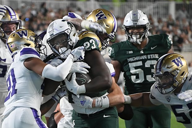 Michigan State tight end Tyneil Hopper (23) gets tackled by Dyson McCutcheon (21) and Jacob Bandes (55) in 2023 in East Lansi