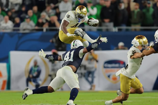 Notre Dame Fighting Irish running back Jeremiyah Love leaps over Penn State Nittany Lions linebacker Kobe King