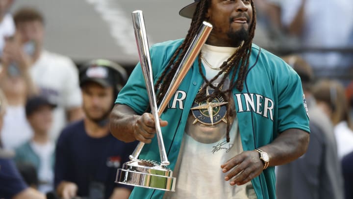 Jul 10, 2023; Seattle, Washington, USA; Former Seattle Seahawks running back Marshawn Lynch brings the championship trophy to the field before the finals of the All-Star Home Run Derby at T-Mobile Park.  Mandatory Credit: Joe Nicholson-USA TODAY Sports