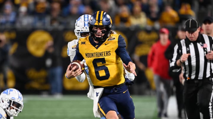 Dec 27, 2023; Charlotte, NC, USA; West Virginia Mountaineers quarterback Garrett Greene (6) with the ball as North Carolina Tar Heels linebacker Power Echols (23) and defensive back Marcus Allen (29) defend in the third quarter at Bank of America Stadium. 