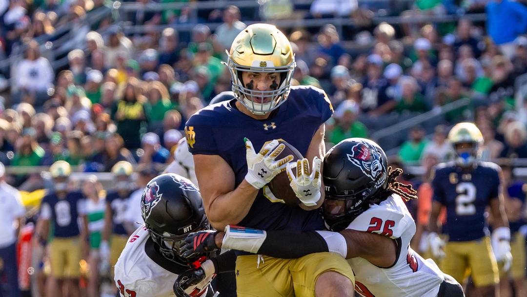 Oct 11, 2025; South Bend, Indiana, USA; Notre Dame Fighting Irish tight end Eli Raridon (9) competes a pass while NC State Wolfpack linebacker Jr. Kenny Soares (33) and defensive back Asaad Brown Jr. (26) tackle him during the first half at Notre Dame Stadium. Mandatory Credit: Michael Caterina-Imagn Images
