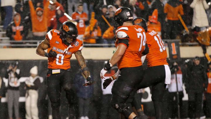 Nov 25, 2023; Stillwater, Oklahoma, USA;  Oklahoma State's Ollie Gordon II (0) celebrates with Oklahoma State's Preston Wilson (74) and Rashod Owens (10) after scoring a touchdown during the second overtime against the Brigham Young Cougars at Boone Pickens Stadium. Mandatory Credit: Sarah Phipps-USA TODAY Sports