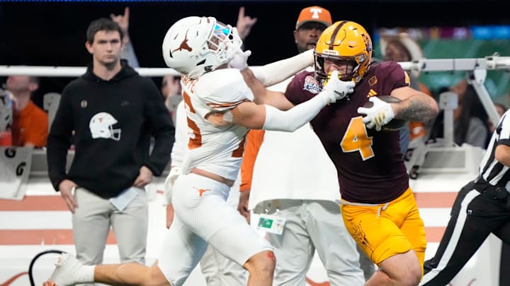 Arizona State running back Cam Skattebo (4) has his face mask grabbed after a catch by Texas defensive back Andrew Mukuba (4) during the fourth quarter in the Chick-fil-A Peach Bowl in Atlanta on Wednesday, Jan. 1, 2025.