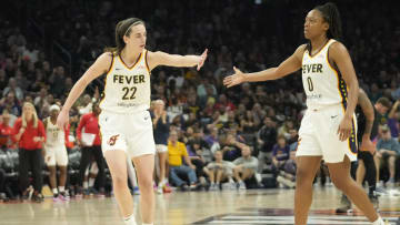 Indiana Fever guard Caitlin Clark (22) slaps hands with guard Kelsey Mitchell (0).