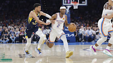 Oklahoma City Thunder guard Shai Gilgeous-Alexander drives to the basket beside Indiana Pacers guard Tyrese Haliburton.