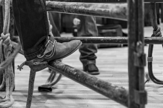 A cowboy boot with a spur on it leaned on a panel.