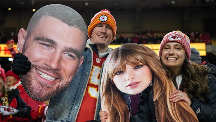 Chiefs fans wave Taylor Swift and Travis Kelce cutouts at Arrowhead Stadium.