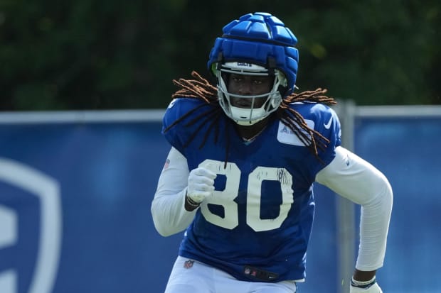 Football player Jelani Woods runs a drill during practice in a blue jersey.